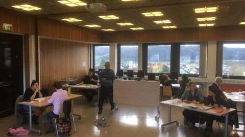 Teilnehmer und Teilnehmerinnen der Prozessentwicklungsgruppe sitzen an Tischen und arbeiten in Kleingruppen, die aus zwei Personen bestehen.