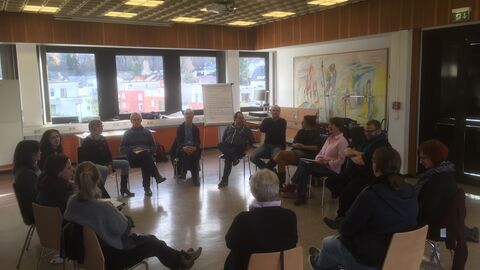 Teilnehmer und Teilnehmerinnen der Prozessentwicklungsgruppe sitzen in einem Stuhlkreis zusammen.
