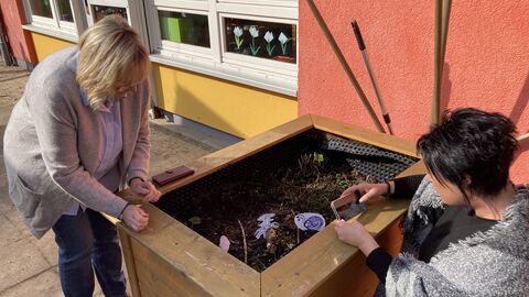 Teilnehmerinnen und Teilnehmer des Basisworkshops im Garten bei der Erstellung eines Bilderbuchs. Hier am Hochbeet.