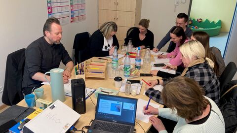 Vorbereitungsphase für einen Praxisteil des Workshops Mehrere Personen sitzen an einem Tisch und malen