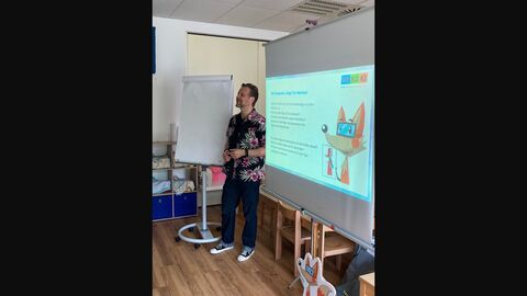 Referent Jan Rathje steht vor einer Leinwand auf der ein Ausschnitt seiner Präsentation zu sehen ist. 