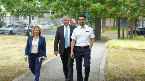 Staatsminister Prof. Dr. Poseck, Polizeivizepräsidentin des Polzeipräsidiums Westhessen,Thaler und ein Polizeibeamter gehen einen Weg entlang